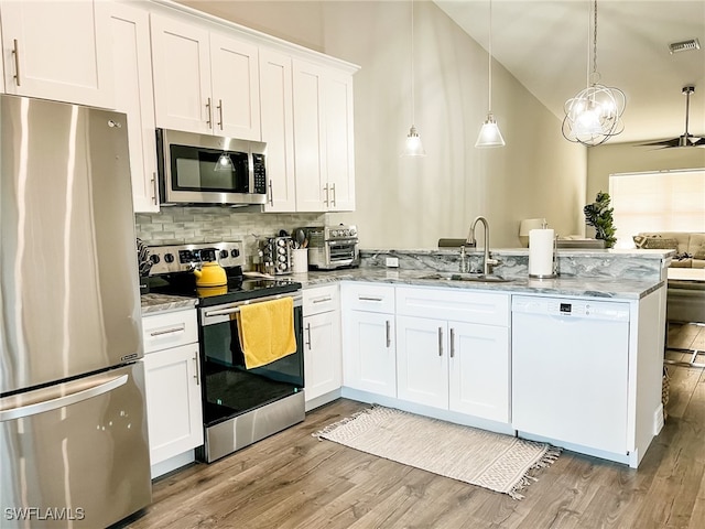 kitchen with kitchen peninsula, appliances with stainless steel finishes, pendant lighting, light hardwood / wood-style flooring, and white cabinetry