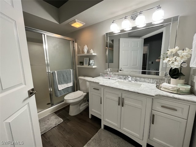 bathroom with wood-type flooring, vanity, toilet, and a shower with door