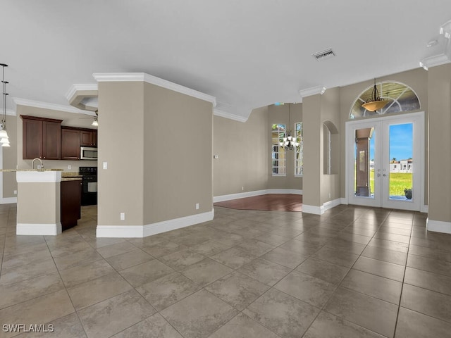 unfurnished living room with an inviting chandelier, crown molding, sink, and french doors