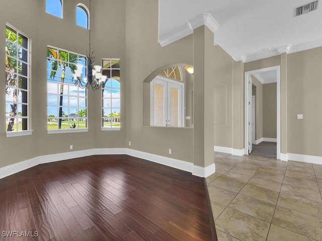 empty room with crown molding, hardwood / wood-style floors, and a notable chandelier