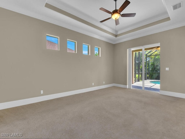 carpeted empty room featuring a tray ceiling, ceiling fan, and crown molding