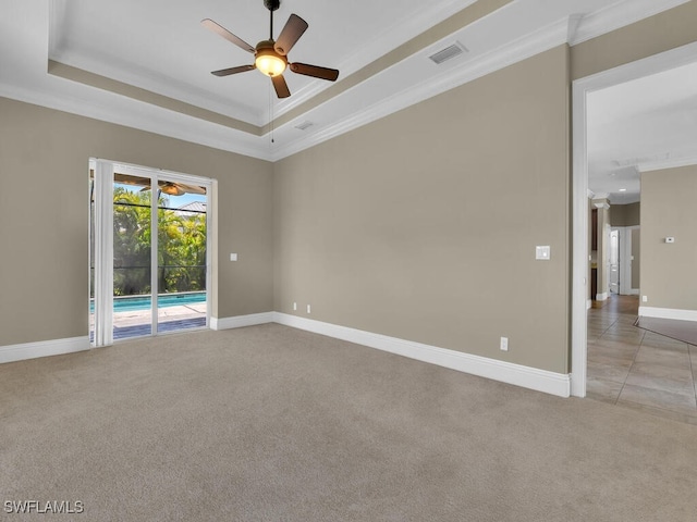 empty room featuring ceiling fan, light colored carpet, a tray ceiling, and crown molding