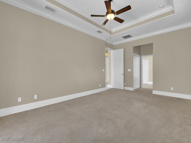 carpeted spare room with ceiling fan, a tray ceiling, and crown molding