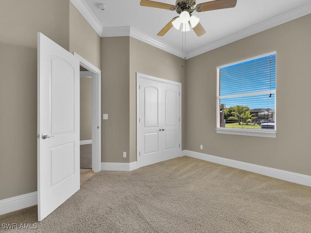 unfurnished bedroom featuring ornamental molding, ceiling fan, light colored carpet, and a closet