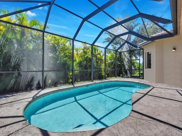 view of swimming pool with glass enclosure and a patio