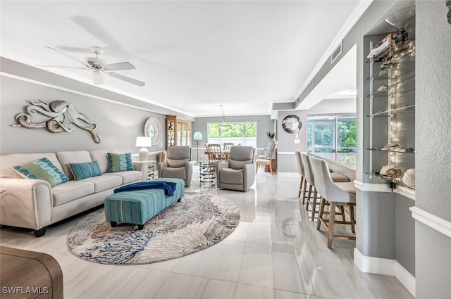 tiled living room with ornamental molding and ceiling fan