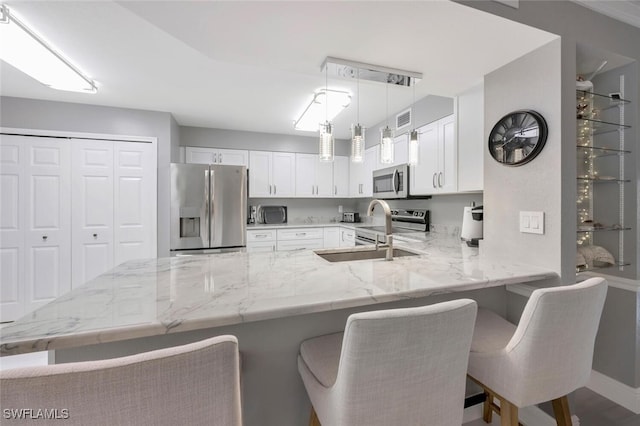 kitchen with kitchen peninsula, a breakfast bar area, stainless steel appliances, and white cabinets