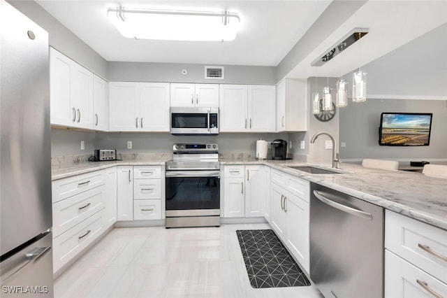 kitchen featuring light stone counters, sink, white cabinets, hanging light fixtures, and appliances with stainless steel finishes