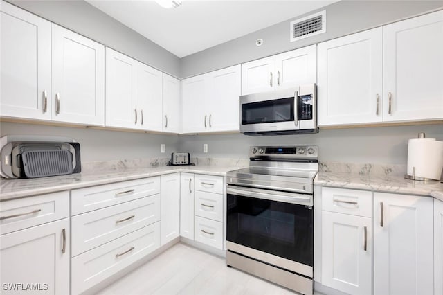 kitchen with white cabinets, stainless steel appliances, and light stone countertops