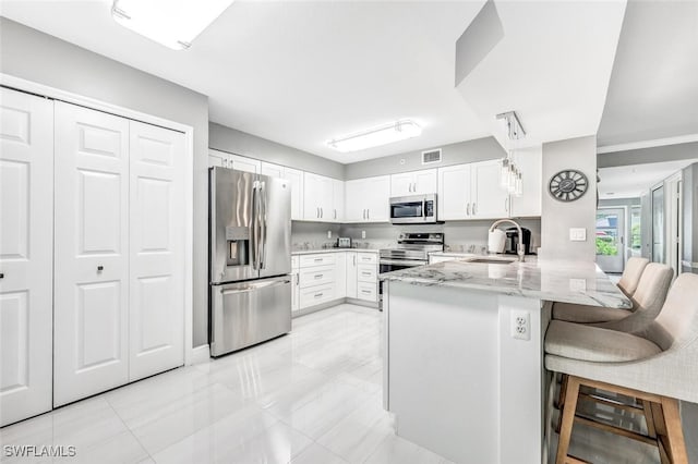 kitchen featuring a breakfast bar, sink, white cabinets, kitchen peninsula, and stainless steel appliances