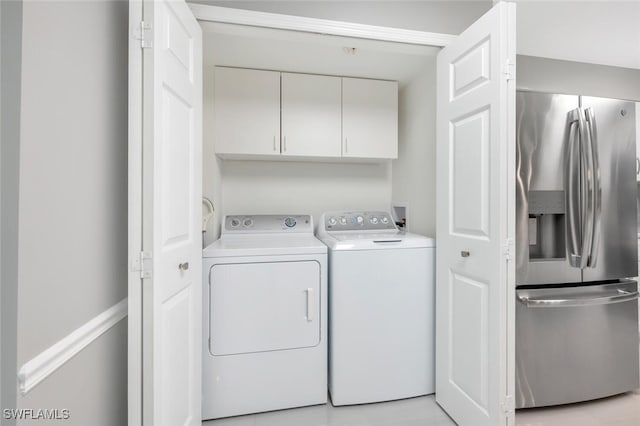 clothes washing area with cabinets and separate washer and dryer