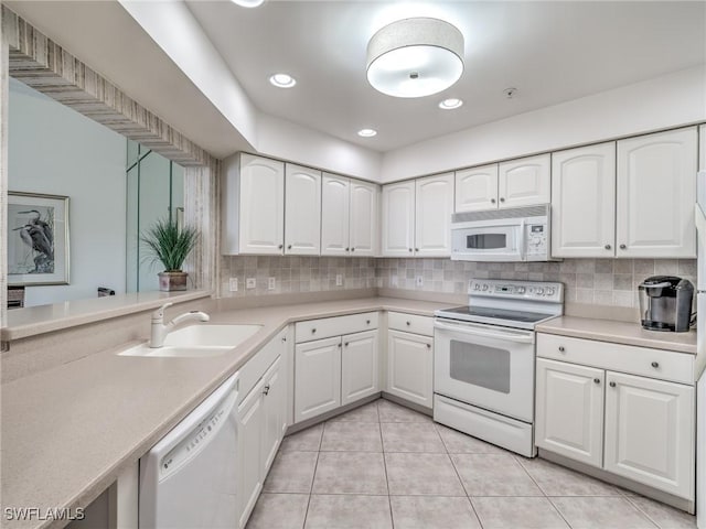 kitchen with white appliances, a sink, white cabinetry, light countertops, and decorative backsplash