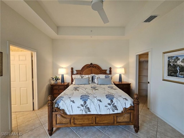 bedroom with a tray ceiling, visible vents, a spacious closet, and light tile patterned floors