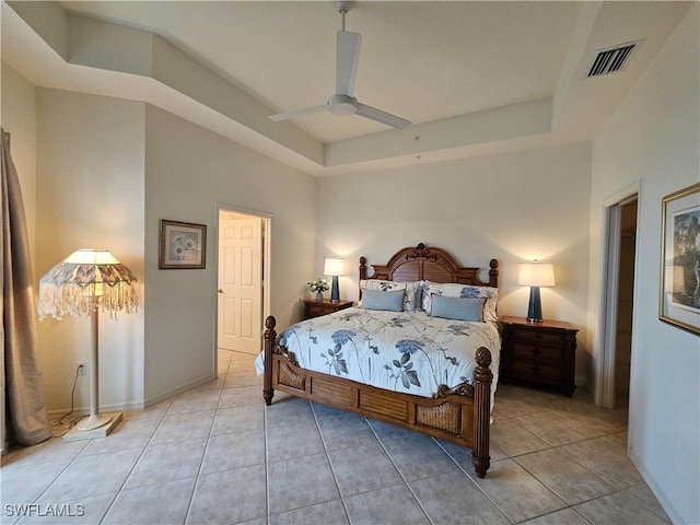 bedroom with a tray ceiling, visible vents, and light tile patterned floors