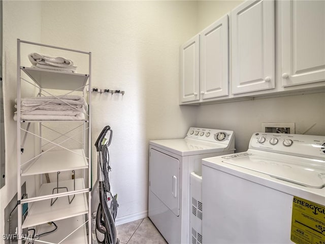 laundry area with washing machine and dryer, cabinet space, baseboards, and light tile patterned flooring