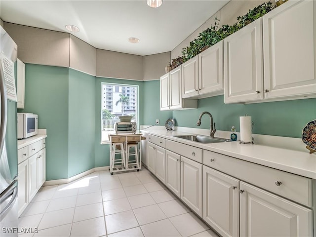 kitchen featuring light countertops, a sink, and white cabinetry