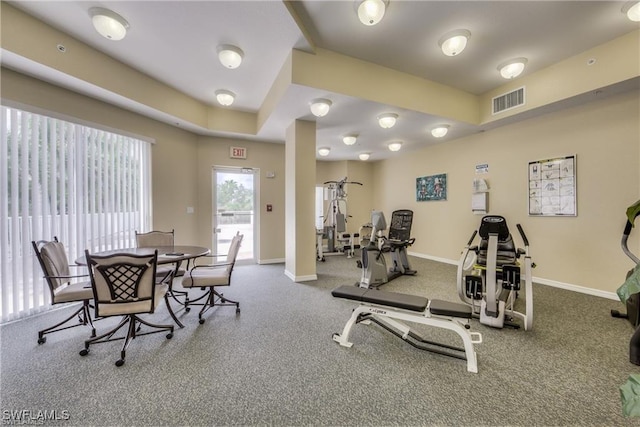 exercise room with baseboards, visible vents, and a tray ceiling