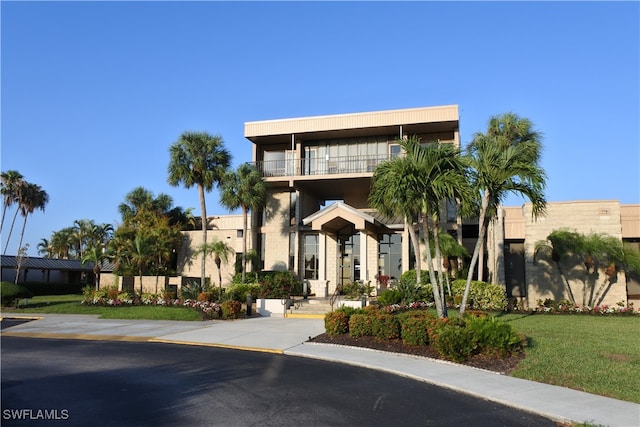 view of front facade featuring a balcony and a front yard