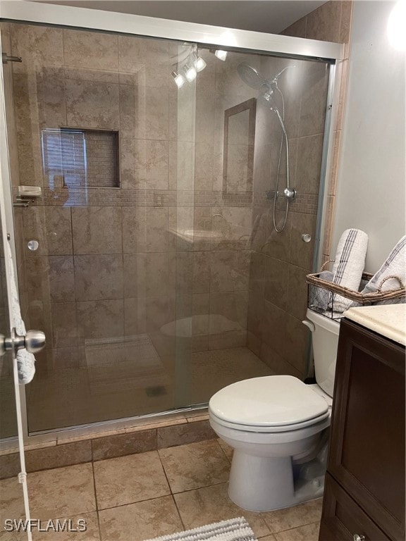 bathroom featuring tile patterned flooring, a shower with shower door, vanity, and toilet