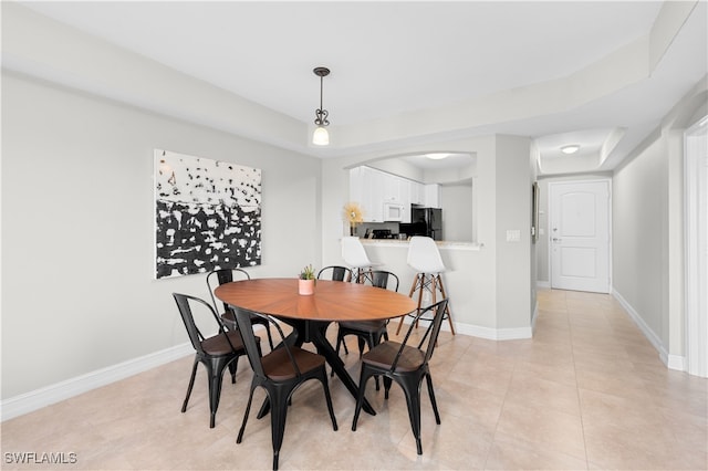 tiled dining area with a tray ceiling