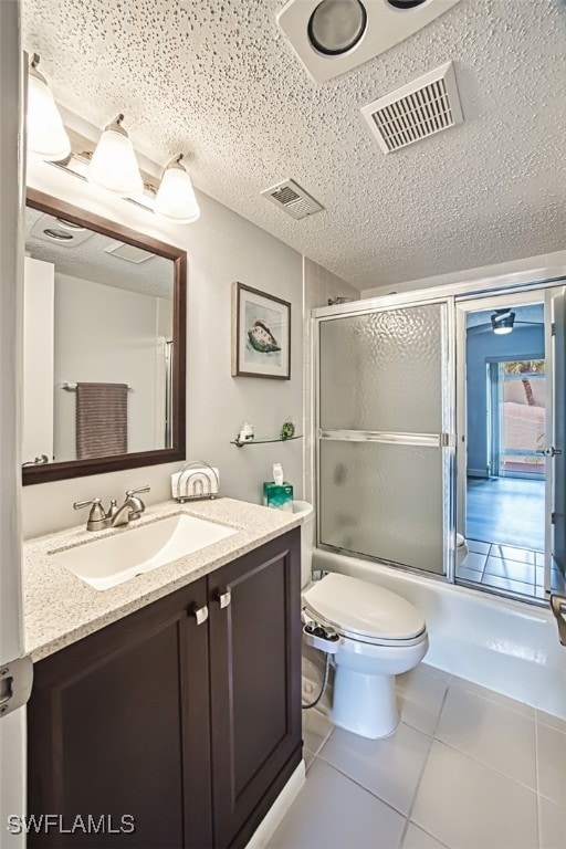 full bathroom with tile patterned flooring, enclosed tub / shower combo, a textured ceiling, toilet, and vanity