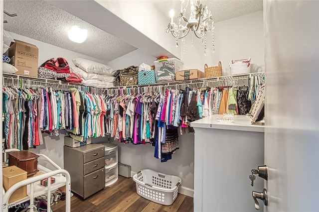 spacious closet with dark hardwood / wood-style flooring and a notable chandelier