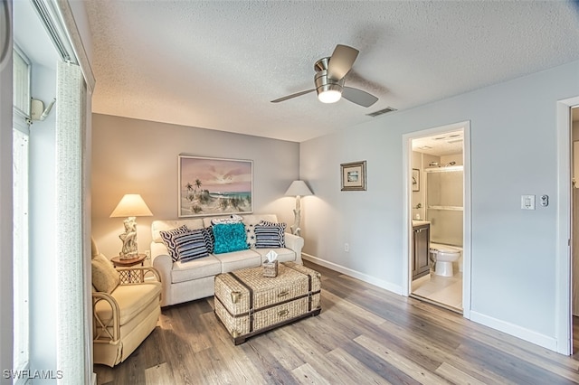 living room with a textured ceiling, hardwood / wood-style flooring, and ceiling fan