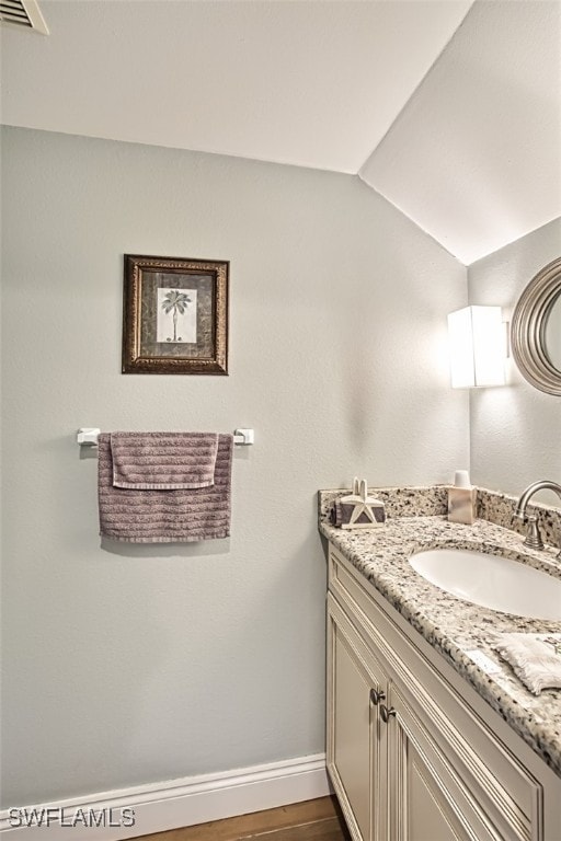 bathroom featuring hardwood / wood-style floors, vanity, and vaulted ceiling