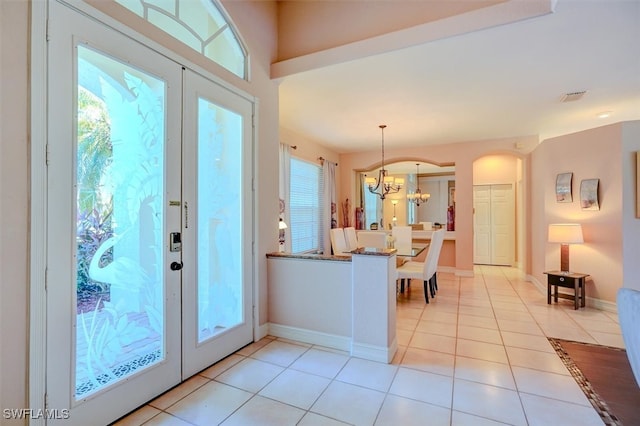 tiled foyer featuring a notable chandelier, french doors, and plenty of natural light