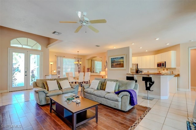 living room featuring ceiling fan with notable chandelier, light tile patterned floors, and french doors