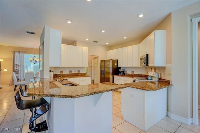 kitchen with sink, kitchen peninsula, stainless steel appliances, a breakfast bar, and dark stone countertops