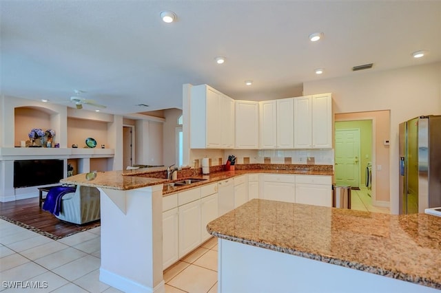 kitchen with kitchen peninsula, light stone countertops, light tile patterned floors, ceiling fan, and stainless steel refrigerator with ice dispenser