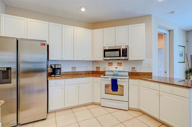 kitchen with appliances with stainless steel finishes, dark stone counters, and white cabinetry