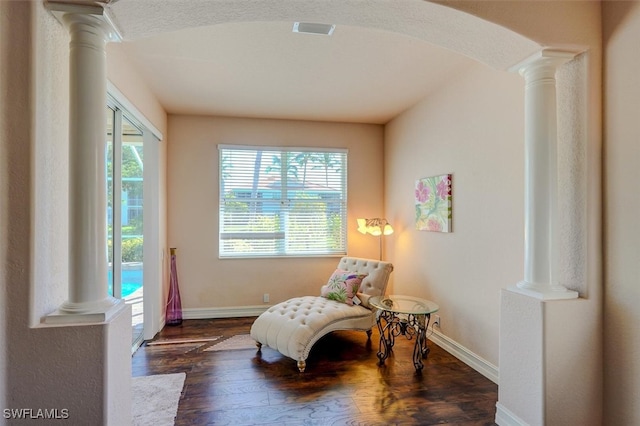 sitting room featuring decorative columns and dark wood-type flooring