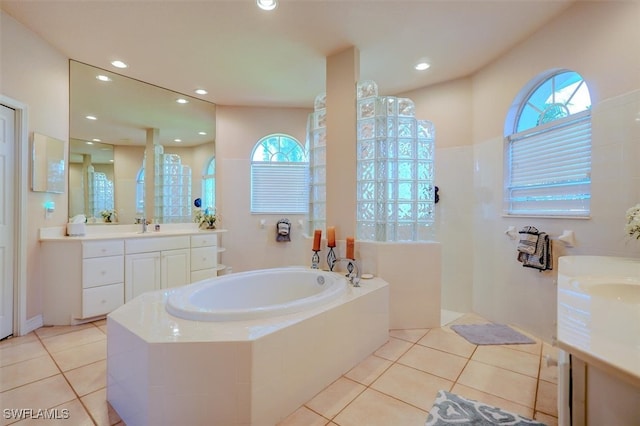 bathroom with tiled tub, vanity, and tile patterned floors