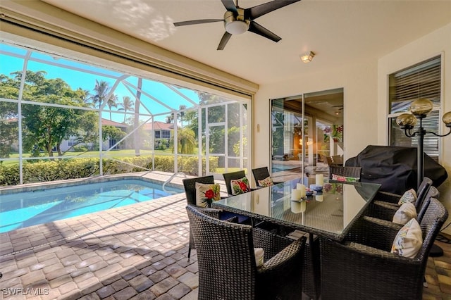 view of swimming pool with glass enclosure, area for grilling, ceiling fan, and a patio