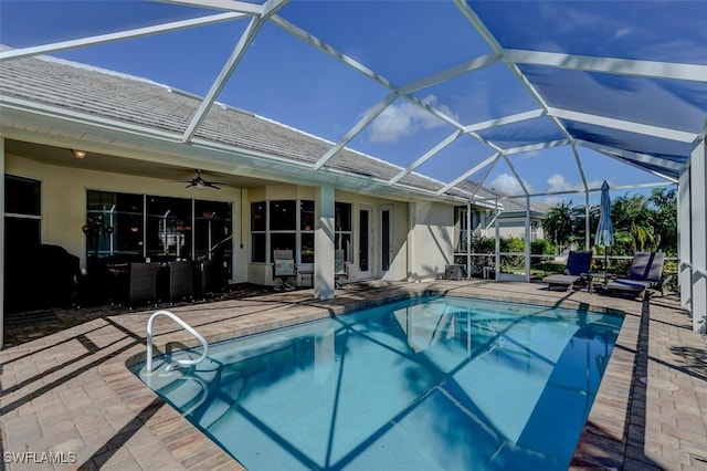 view of pool featuring glass enclosure, ceiling fan, and a patio area