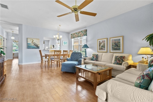 living room with light hardwood / wood-style floors, ceiling fan with notable chandelier, and a healthy amount of sunlight