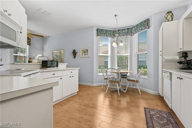 kitchen with light hardwood / wood-style floors, white cabinets, hanging light fixtures, and white appliances