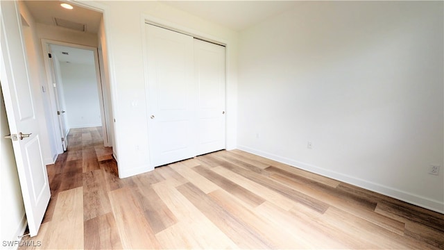 unfurnished bedroom with light hardwood / wood-style flooring and a closet