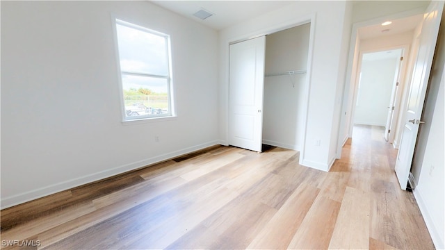 unfurnished bedroom with light wood-type flooring and a closet