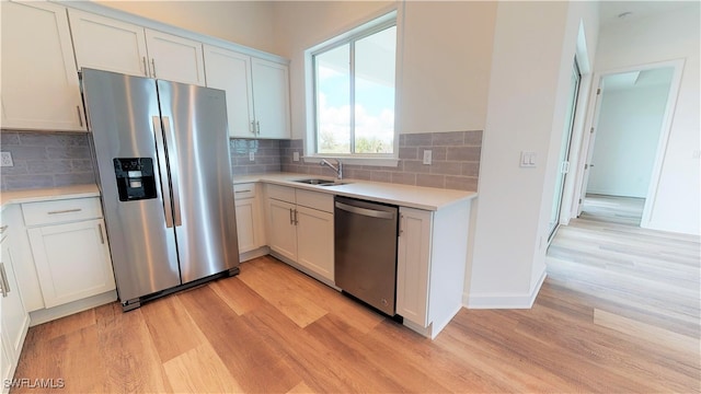 kitchen with stainless steel appliances, white cabinets, light hardwood / wood-style floors, and sink