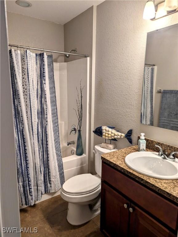 full bathroom with vanity, shower / tub combo, tile patterned floors, and toilet