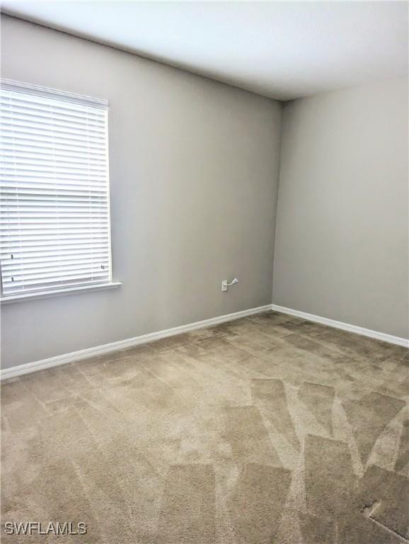 carpeted spare room featuring baseboards