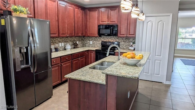 kitchen featuring decorative light fixtures, tasteful backsplash, an island with sink, sink, and black appliances