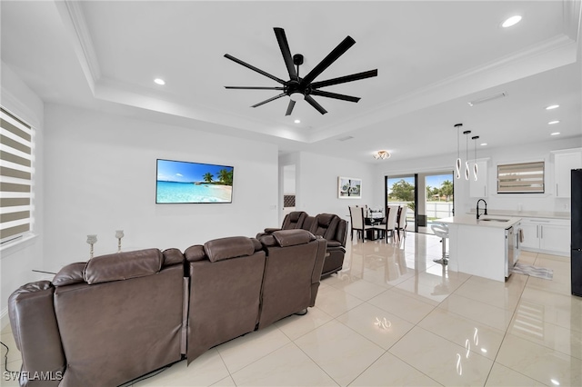 living room featuring ceiling fan, sink, a tray ceiling, and light tile patterned floors