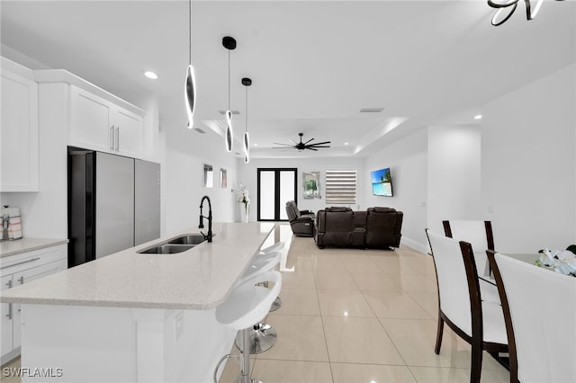 kitchen with sink, white cabinetry, decorative light fixtures, ceiling fan, and stainless steel fridge