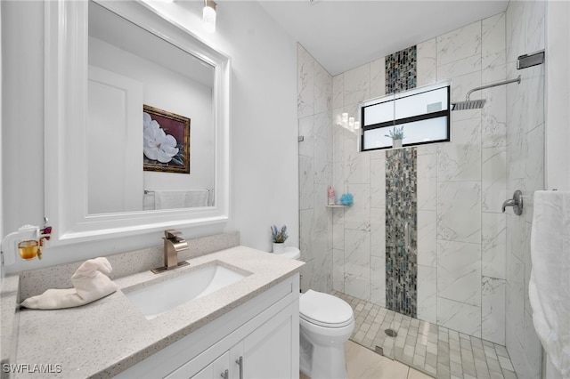 bathroom featuring tiled shower, vanity, toilet, and tile patterned flooring