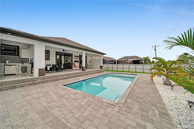 view of pool with ceiling fan, sink, a patio, and exterior kitchen