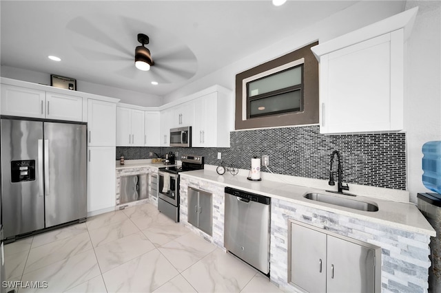 kitchen with white cabinetry, tasteful backsplash, stainless steel appliances, ceiling fan, and sink